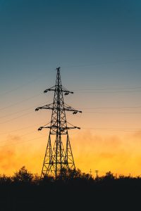 A tall tower sitting next to a forest under a cloudy sky